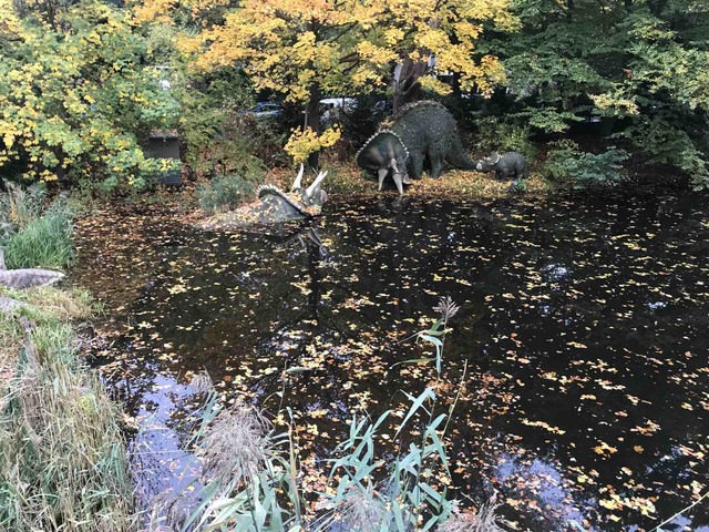 Small park pond with a large dinosaur figure